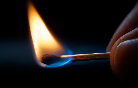 Human Hand Holding a Burning Matchstick with Bright Orange and Blue Flame in Darkness - Powered by Adobe