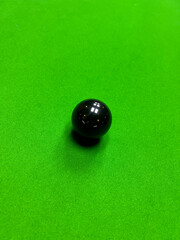 A high-angle, close-up photograph of the green baize of a snooker table. The image clearly shows the black color snooker ball