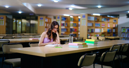 Indian young adult gen z teen age student wear casual glasses sitting on desk table do self study...