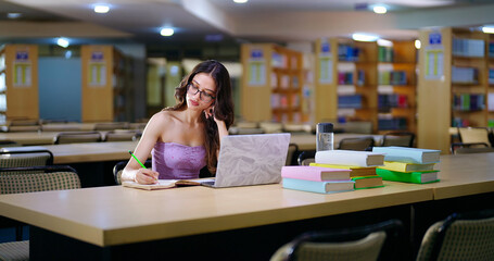 Indian young adult gen z female wear glass look laptop screen use e-learning work study in college...