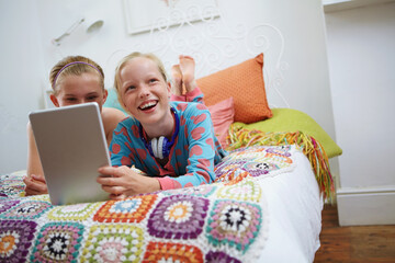 Morning, teen friends and tablet on bed for funny online post, social media or hangout at sleepover. Laugh, girls or relax with digital tech in bedroom for streaming, bonding or weekend break in home