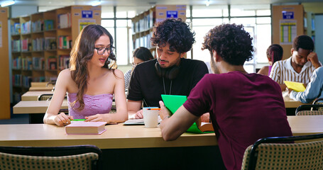 Indian young adult gen z man woman group sitting on desk table chair talk speak do study indoor library teen girl boy male class team guys read book share new work ideas make notes spend day time