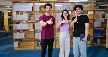 Indian happy young adult gen z male man group standing indoor library look camera spend break time. Asian boy girl great team show thumbs up hand sign staring cam do casual pose enjoy fun joy day © Raushan_films