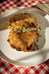 Grilled flatbread sandwich with greens on white plate at restaurant