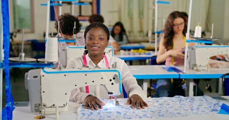 African young adult gen z lady female wear tape around neck look cam indoor class room learn good craft skill sewing machine happy teen girl pupil staring camera do casual pose new college day place