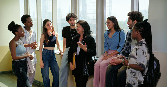 Indian happy young adult tutor lady woman group talk casual gossip have fun joy enjoy new day spend break time indoor place. Teen female girl pupil boy man male guy group mate speak share funny joke