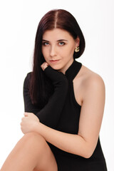 Young woman in black bodysuit posing sitting isolated on white background.