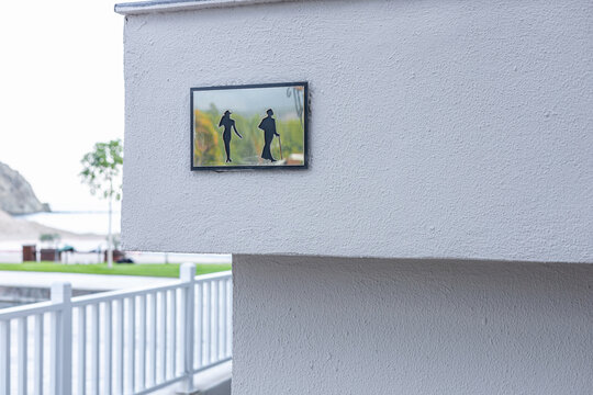 A framed picture of two people walking in a natural setting, displayed on a white wall. The scene captures a serene outdoor atmosphere.