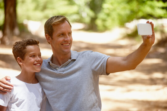 Happy dad, son or forest with selfie for picture, photography or outdoor memory together. Father, child or kid with smile, hug or embrace for capture moment, bonding or family time in nature or woods