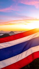 Vibrant Thai Flag Waving Against a Majestic Sunrise Over Misty Mountains.