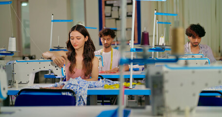 Indian young adult pupil gen z woman wear measure tape around neck sitting class room learn new casual course good sewing machine. focused teen female girl do self craft skill indoor day college place