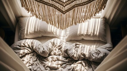 Sunlight streams across a cozy unmade bed with a bohemian macrame hanging overhead.