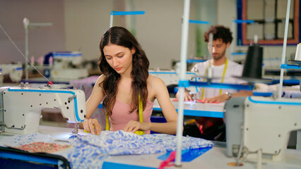 Indian young adult pupil gen z woman wear measure tape around neck sitting class room learn new casual course good sewing machine. focused teen female girl do self craft skill indoor day college place