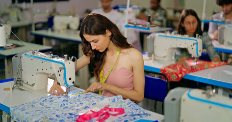 Indian young adult pupil gen z woman wear measure tape around neck sitting class room learn new casual course good sewing machine. focused teen female girl do self craft skill indoor day college place