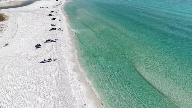 Wide aerial orbit over white sandy beach along the beautiful turquoise Gulf of Mexico with resting visitors, 30A, Florida, USA