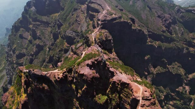 Drone flying backward revealing the stunning hiking trail between pico do arieiro and pico ruivo with its impressive rock formations