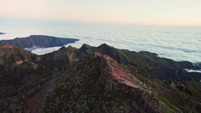 Stunning aerial perspective of madeira's majestic mountains. The camera flies over rugged peaks and green slopes, revealing a vast sea of clouds around pico Ruivo