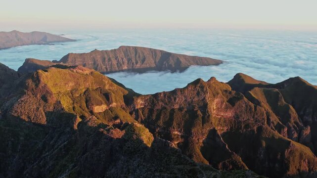 Amazing aerial view of the majestic mountains of pico ruivo on the island of madeira, portugal, soaring above a sea of clouds during a golden sunset