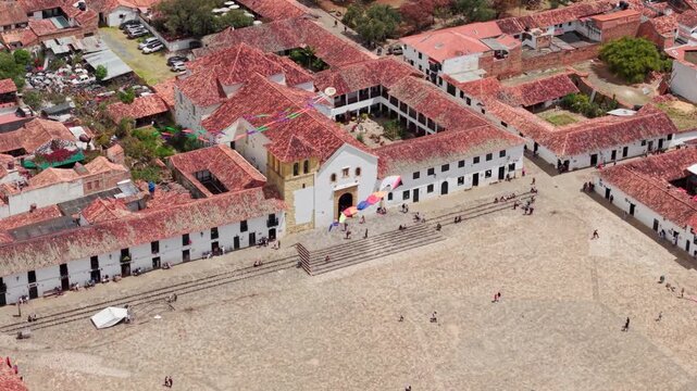 Drone footage showing people flying kites in the historic plaza mayor of villa de leyva, a colombian town