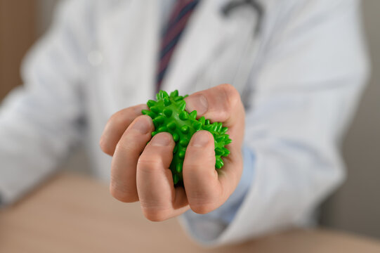An orthopedic doctor demonstrating the use of a rehabilitation ball for squeezing and massage, and grip exercises.