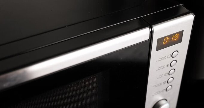 Close up shot of a modern microwave oven with a digital timer counting down. The appliance is actively heating food, showcasing convenience and efficiency in a contemporary
