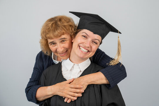 Portrait of Caucasian woman in graduation gown with her mother.