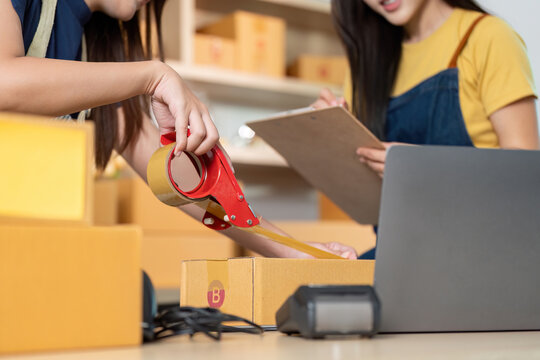 E-commerce. Two women preparing packages for shipment in a modern workspace.