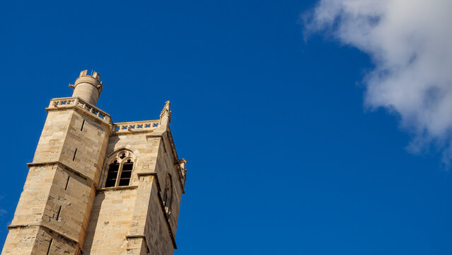 Iconic French Gothic cathedral tower rising into a vast, clear blue sky backdrop