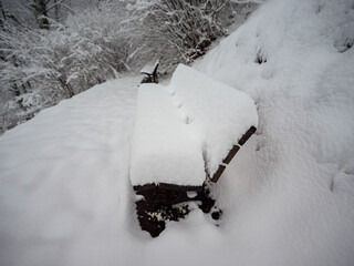 Fresh snow texture covering a wooden park bench on a winter day