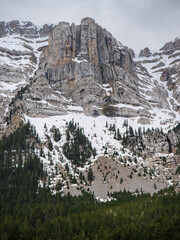 Massive limestone cliff face(Roca Verda with forest and lingering spring snow