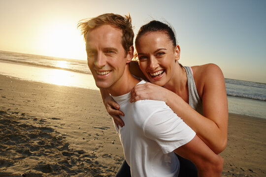 Portrait, couple and happy with piggyback on beach for sunset date, travel adventure and bonding. Love, people and carry partner at seaside for relationship support, summer vacation and connection