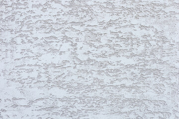 A textured white wall with subtle patterns and variations in tone. The surface appears rough and uneven, creating an interesting visual effect.