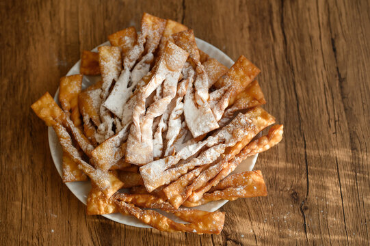 Faworki sprinkled with powdered sugar lying on a plate, a tradition for Fat Thursday