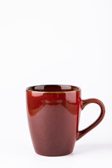 Dark red ceramic mug centered on white background, vertical orientation with copy space. Warm minimalist photo for editorial design or advertising. Concept of morning routine and cozy lifestyle