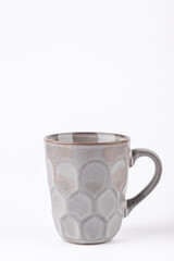 Gray ceramic mug with embossed surface isolated on white background, simple and modern style, vertical composition with copy space. Concept of minimal home decor and warm living