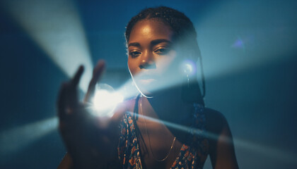 A young Black woman with braided hair reaching out, illuminated by a dramatic spotlight from behind, creating a lens flare effect.