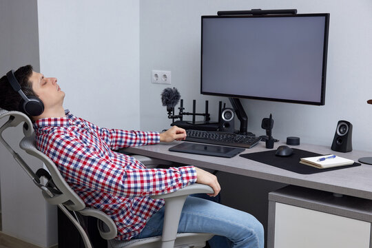 Professional man resting and relaxing in ergonomic office chair with headphones on