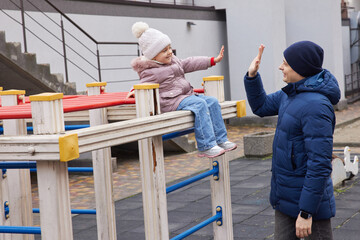 Father and daughter bonding, giving a high five, and playing outdoors during winter