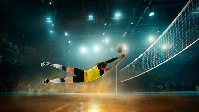 Dramatic composition of female volleyball player diving full-speed across court reaching for ball. Concept of body in motion, professional sports storytelling, and action-oriented promotional visuals.
