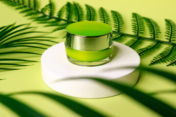 Jar of cosmetic cream on a white round shaped podium around leaves with green background