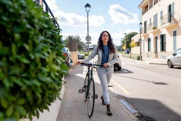 Woman walking bicycle on sidewalk commuting to work