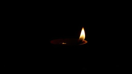 A single candle flame burning brightly in the darkness.