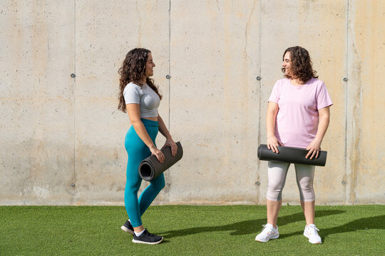 Women friends preparing outdoor fitness activity with mats