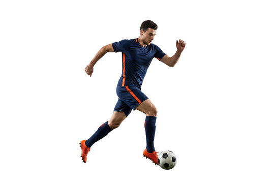 Male soccer player dribbling ball in mid stride on isolated black background, athletic action and competitive sports concept for training, fitness and team game promotion