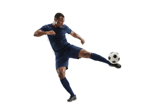 Soccer player kicking ball in mid air on isolated background, athletic action and competitive sports training concept for fitness, agility and team game promotion