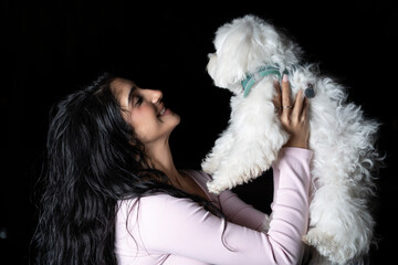 Young woman smiling holding small white dog