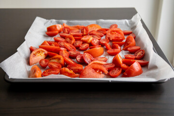 fresh tomato slices and cherry tomatoes on a tray with parchment paper