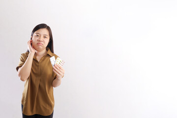 woman holding various medications while touching her swollen cheek after wisdom tooth removal surgery