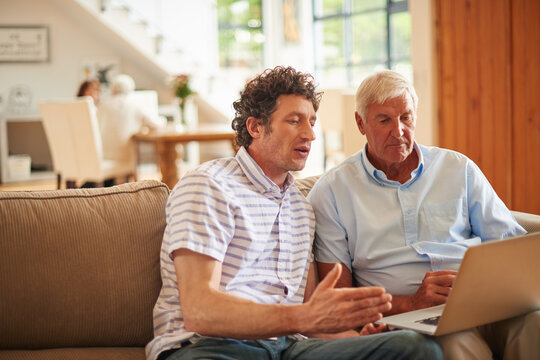 Laptop, teaching and elderly dad with man in home for social media, visit or bonding. Support, family and online with senior father for adult son, tech and help for internet safety for retirement