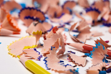Pencil shavings with colorful lead remnants lying on a white surface